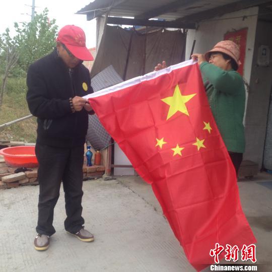 临近国庆，赵伦波老人换了一面新国旗，正在与老伴整理国旗。 刘林 摄