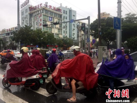 广西沿海居民穿雨衣出行。 翟李强 摄